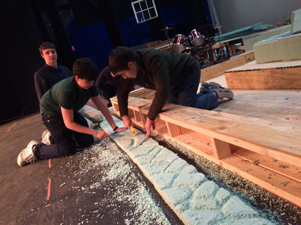 Technical theatre students carve foam that will become the stone wall in the forest. 
