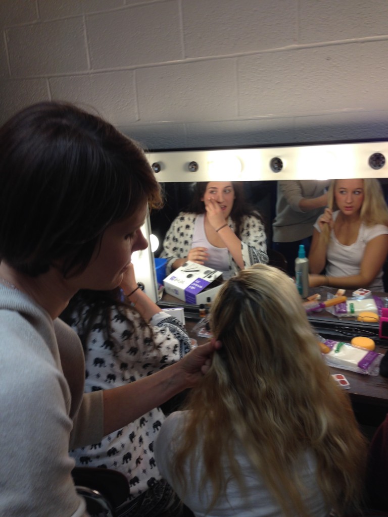 Ms. Evelti helps with braiding hair backstage. 