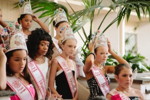 Emily, 11, poses for a photo with her fellow competitors. Emily is not pleased with the outcome of this pageant-- she had hoped to get a higher title. Emily Dextraze is an eleven-year-old beauty pageant competitor who lives in Westfield, Massachusetts, a small town of 42,000 people in Western New England located about two hours west of Boston, Massachusetts. The beauty pageant industry in the United States is estimated to be worth 5 billion U.S. dollars annually; the estimated number of pageants in the U.S. ranges from 5,000 to 100,000, according to an Internet search. It is conservatively estimated that 2.5 million American girls, from babies to teenagers, participate. The cost to a family for a daughter to participate in a pageant ranges from $1500 to considerably more. Entry fees, elaborate costumes, makeup, hairdressing, artificial tans and weeks of professional coaching contribute to the high cost. Photo by Ilana Panich-Linsman